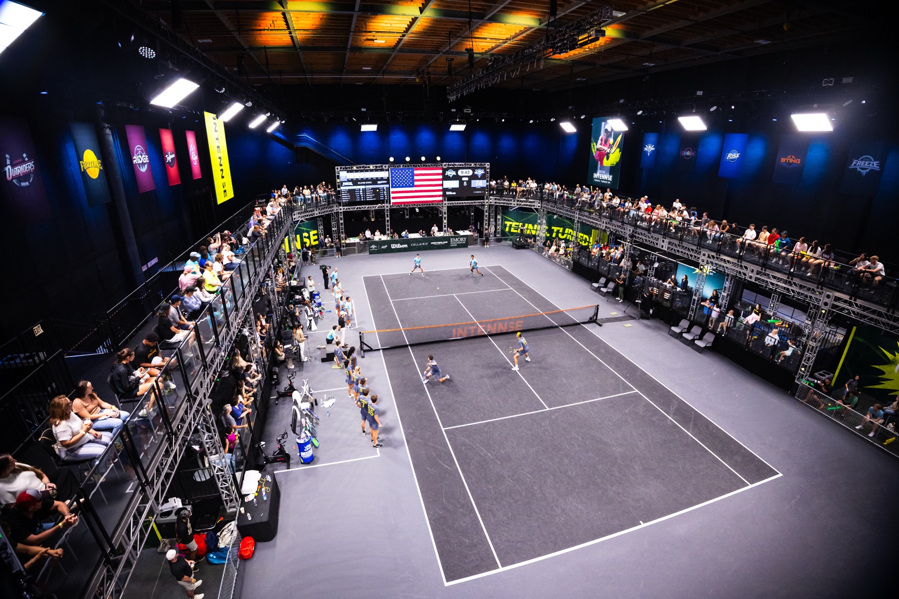 Wide view of the INTENNSE Arena during a match, court lit and stands full.